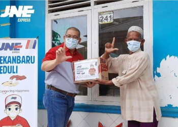 Pimpinan Cabang JNE Pekanbaru, Hui Mandra (kiri) saat menyalurkan bantuan ke masyarakat, April 2020.