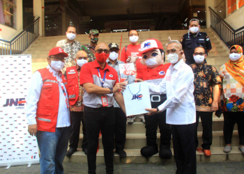 Project Brand Specialist JNE Yance Arvan (kiri) menyerahkan masker kepada Ketua Pengurus PMI Jakarta Pusat, Soewardi Sulaeman