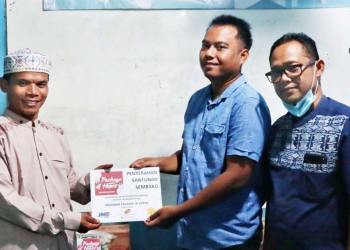 Deputy Branch Head JNE Bogor Ade Kurniawan (kanan) menyerahkan santunan kepada Kepala Yayasan Ar-Rohmat , Ustadz Ues.