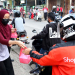 Para Ksatria dan Srikandi JNE Bogor tengah membagi-bagikan makanan kepada pengendara yang lewat dalam kegiatan Jumat Berkah