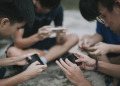 an asian chinese group of teenage boys playing mobile game in the basketball court after school using phone