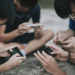 an asian chinese group of teenage boys playing mobile game in the basketball court after school using phone