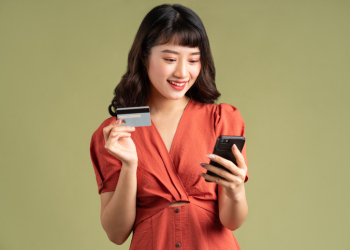 Asian woman holding a bank card and staring at her phone