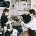 Asian woman cafe owner businesswoman receiving payment from her customer at counter using QR code contactless payment , Two woman wearing a facemask to avoid the spread of coronavirus COVID-19 lifestyle concepts- stock photo