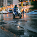 Unrecognizable person riding motorcycle on wet road in rainy season