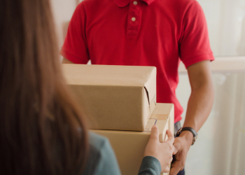 young asian woman customer receive parcel post box from home delivery service man in red uniform at home, express home delivery service, cargo shipping, transport logistics and online shopping concept