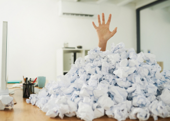 Shot of an unidentifiable businesswoman drowning under a pile of paperwork in the office