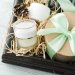 Beauty products, gift with green ribbon and pine cones composition on shabby white wooden table. Top view