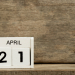 White block calendar present date 21 and month April on wood background