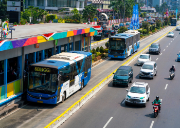 Jakarta, Indonesia - August 20, 2018: view showing Transjakarta bus stop shelter, cars and motorcycle on the other way of Jakarta street