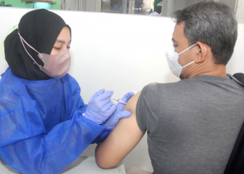 Salah seorang tenaga medis sedang menyuntikkan vaksin dalam program vaksinasi booster yang digelar JNE.