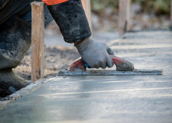A construction worker is Smoothing wet cement