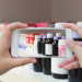 Female hand hold mobile smart phone taking photo of medicine bottles on the pharmacy store shelves