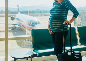 Pregnant woman at second trimester traveling by plane. Mother to be going to vacation or business trip. Is it safe to travel during pregnancy concept