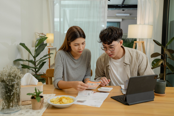 Happy young couple using laptop pay bills online in app calculate  investment payment budget discuss finances at home.